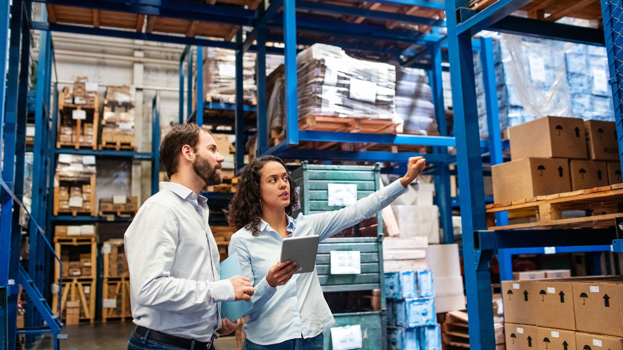 Coworkers looking at stock in warehouse